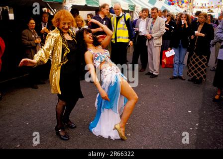 Ann Barr (16. September 1929 – 4. Mai 2015) Redakteur, Journalistin, Schriftstellerin, Schöpferin des „Sloane Ranger“ auf der jährlichen Straßenparty Motcomb Street, die mit einem Bauchtänzer tanzt. Die Straße ist ein Dorf mit Restaurants, Bars, Antiquitätenläden und Kunstgalerien; ein florierender Ort, der nicht von den Superreichen übernommen wurde, sondern nur von den wohlhabenden Knightsbridge und libanesischen Massen. Belgravia, London, England, ca. Juli 1998. HOMER SYKES Stockfoto