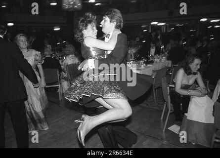 Ein wohlhabendes junges Paar Sloane Rangers geht auf die Tanzfläche beim alljährlichen Rosenball der Wohltätigkeitsorganisation, der im Grosvenor House Hotel, Park Lane, stattfindet. Mayfair, London, England, ca. Mai 1982. Stockfoto