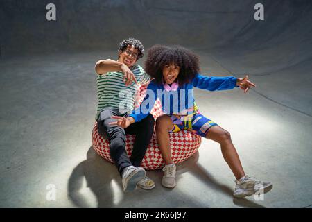 Porträt coole, begeisterte junge Freunde, die auf dem Sitzsack Gesten Stockfoto