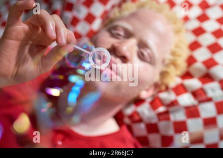 Ein junger Mann bläst Blasen mit einem Blasenstab Stockfoto