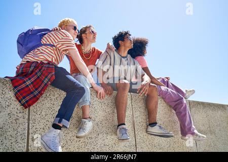 Junge Freundinnen hängen rum, sitzen auf einem sonnigen Felsvorsprung Stockfoto