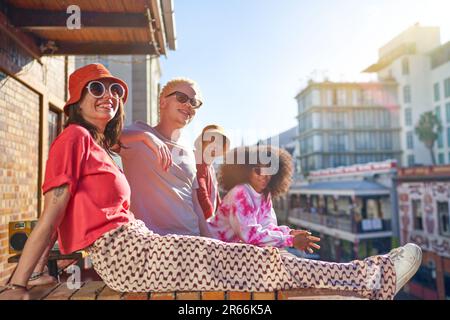 Fröhliche, coole, junge Freunde, die auf dem sonnigen Balkon der Stadt abhängen Stockfoto