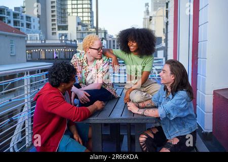 Glückliche junge Freunde, die auf dem urbanen Balkon abhängen Stockfoto