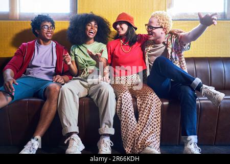 Porträt fröhliche junge Freunde, die auf der Bank lachen Stockfoto