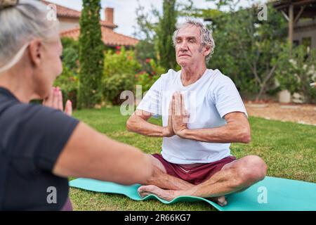 Ruhiges Seniorenpaar, das im Sommergarten meditiert Stockfoto