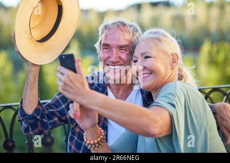 Glückliches Seniorenpaar, das Selfie auf dem Balkon macht Stockfoto