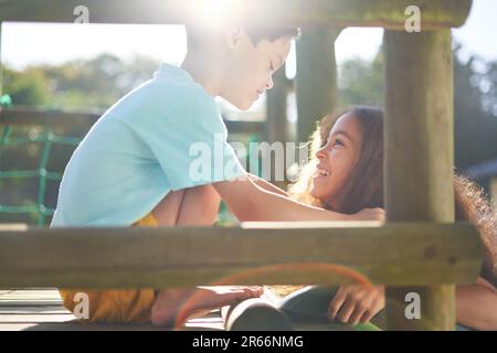 Glückliche Schwester und Bruder mit Down-Syndrom oben auf der sonnigen Rutsche Stockfoto