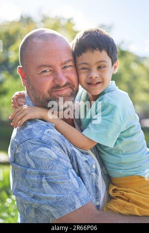 Porträt lächelnder Vater hält süßen Sohn mit Down-Syndrom Stockfoto