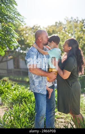 Eltern, die Sohn mit Down-Syndrom im sonnigen Garten haben Stockfoto