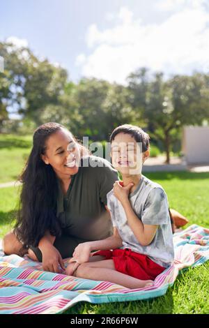 Portrait happy mother and son with Down Syndrome in sunny park Stock Photo