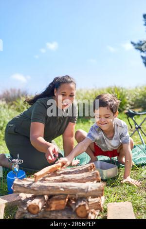 Mutter und Sohn mit Down-Syndrom, die Feuerholz auf dem Campingplatz stapeln Stockfoto