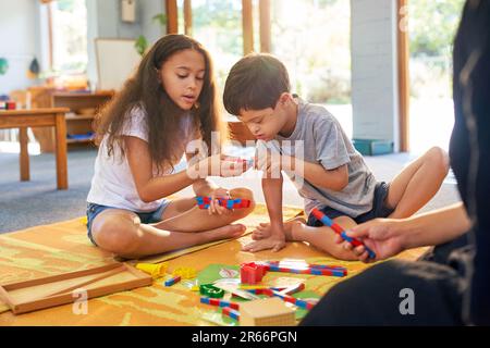 Schwester und Bruder mit Down-Syndrom spielen mit Spielzeug auf dem Boden Stockfoto