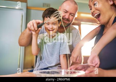 Glücklicher Junge mit Down-Syndrom, der mit der Familie zu Hause gebacken hat Stockfoto