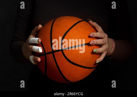 Concept Frauensport. Hände halten den Ball. Eine Hand in Kassetten. Second Hand mit Maniküre Stockfoto