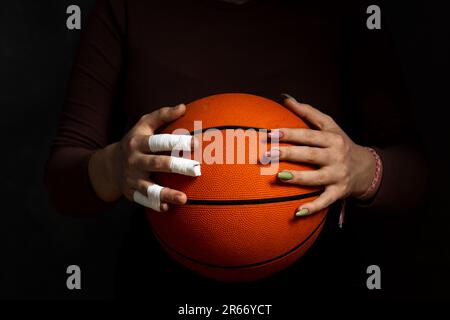Concept Frauensport. Hände halten den Ball. Eine Hand in Kassetten. Second Hand mit Maniküre Stockfoto