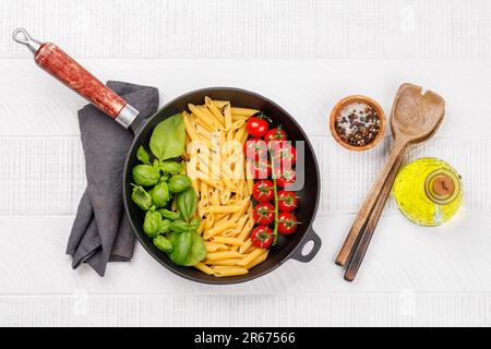 Eine lebendige Darstellung der italienischen Flagge mit Pasta, Basilikum und Tomaten, wunderschön präsentiert in einer Pfanne. Flach verlegt Stockfoto