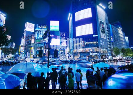 Shibuya Scramble Crossing überfüllt in einer regnerischen Nacht Stockfoto