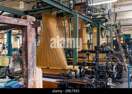 Dieses Bild zeigt eine moderne Industriemaschine, mit der kegelförmige Garnspulen hergestellt werden, die für Strickprojekte erforderliches Material liefern Stockfoto