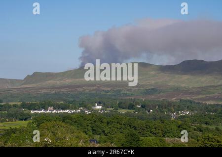 Killearn, Stirling, Schottland, Großbritannien. 7. Juni 2023. Der schottische Feuerwehr- und Rettungsdienst hat eine schottische Warnung vor einem „sehr hohen“ Wildbrandrisiko herausgegeben. Abbildung: Rauchwolken von einem Lauffeuer auf den Campsie Fells, wie sie heute Nachmittag über dem Dorf Killearn zu sehen sind. Scottish Fire and Rescue haben gesagt, dass „aufgrund von Wasserbomben mit dem Hubschrauber, wir empfehlen Anwohnern, die Gegend zu meiden und Fenster und Türen geschlossen zu halten“. Kredit: Kay Roxby/Alamy Live News Stockfoto