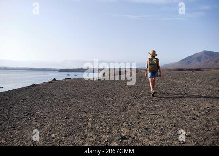 Eine Frau, die auf einer Klippe spaziert und den Sonnenuntergang über dem Meer sieht. Reisen und Tourismus. Stockfoto