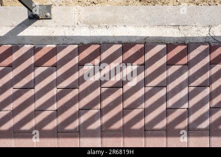 Braune Pflastersteine mit Schatten von einem Geländer Stockfoto