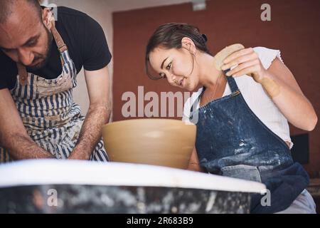 Zu haben und zu Formen. Ein junger Mann und eine junge Frau, die mit Ton in einem Töpferstudio arbeiten. Stockfoto