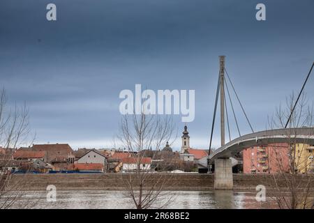 Bild einer Hängebrücke in der Stadt Sremska Mitrovica im Norden Serbiens, die den Fluss Sava überquert, mit dem Stadtzentrum der Stadt in Srems Stockfoto