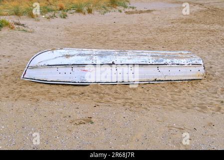 Ein kleines weißes Boot gekentert am Strand oder in der Wüste Stockfoto