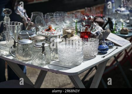 Glasgeschirr, Bierbecher und Trinkgläser sowie anderes Geschirr auf einem Tisch auf einem Flohmarkt an einem sonnigen Tag, ausgewählter Fokus, enge Tiefe von Fi Stockfoto