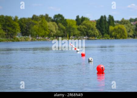 Schwimmende Bälle in Rot und Weiß markieren die Ziellinie auf dem See während eines Ruderregattas, Kopierraum, ausgewählter Fokus, schmale Schärfentiefe Stockfoto