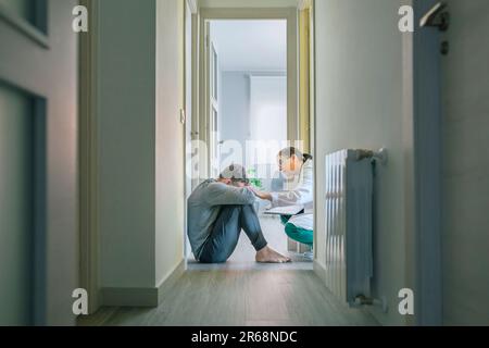 Arzt beruhigt und hilft Patienten beim Sitzen auf dem Zimmerboden Stockfoto