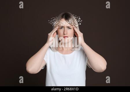 Das Amnesiekonzept. Eine Frau, die versucht, sich an etwas auf dunklem Hintergrund zu erinnern. Kranz von Fragezeichen symbolisieren Gedächtnisverlust Stockfoto