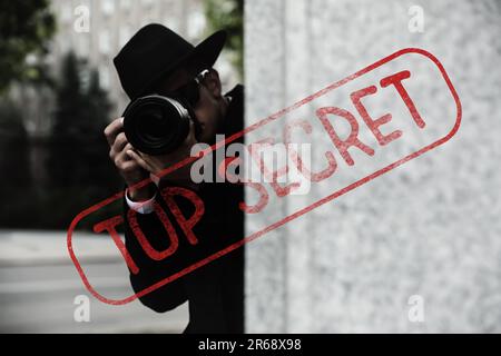 Geheime Informationen. Privatdetektiv mit Kamera, ermittelt auf der Straße der Stadt. Stempel Streng Geheim Stockfoto