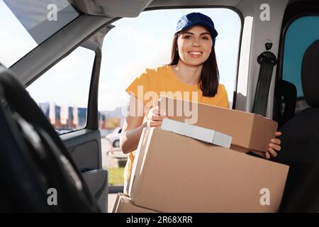 Der Kurier nimmt das Paket vom Auto ab. Lieferservice Stockfoto