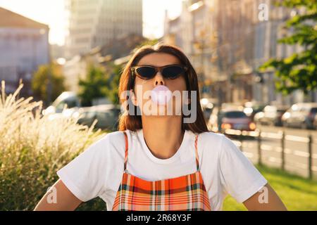 Schöne Frau, die Kaugummi auf der Straße bläst Stockfoto