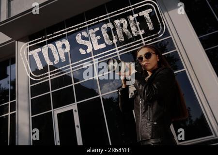 Geheime Informationen. Privatdetektiv mit Kamera, der in der Nähe eines Gebäudes auf der Straße der Stadt ermittelt. Stempel Streng Geheim Stockfoto