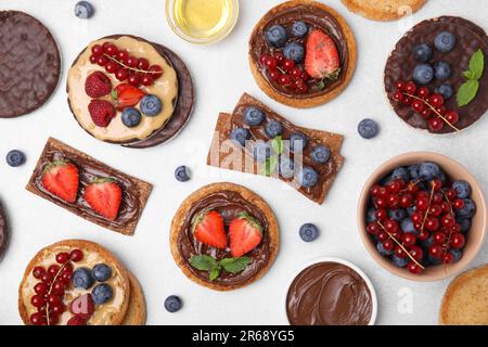 Frisches Roggen-Knusperbrot, knusprige Reiskuchen und Zwieback mit verschiedenen Belägen auf hellgrauem Tisch, flach liegend Stockfoto