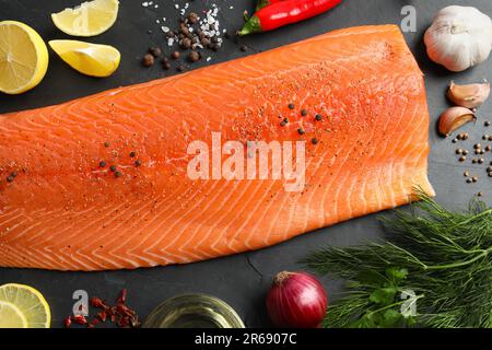 Frischer roher Lachs und Zutaten für Marinade auf schwarzem Tisch, flach liegend Stockfoto