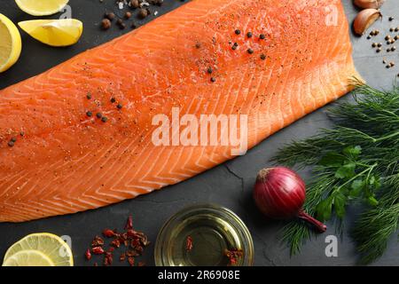 Frischer roher Lachs und Zutaten für Marinade auf schwarzem Tisch, flach liegend Stockfoto