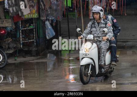 SAMUT PRAKAN, THAILAND, MAI 10 2023, Männer in Militäruniformen fahren Motorrad im Regen Stockfoto