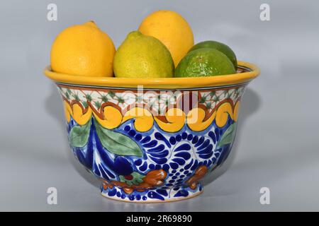 Zitronen und Limetten in einer dekorativen Keramikschüssel. Stockfoto