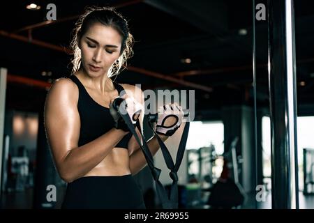 Sportliche Frau trainiert auf Multistation im Fitnessstudio für Arm- und Schultermuskulatur. Fitness-Training im Fitnessstudio. Stockfoto