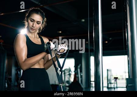 Sportliche Frau trainiert auf Multistation im Fitnessstudio für Arm- und Schultermuskulatur. Fitness-Training im Fitnessstudio. Stockfoto