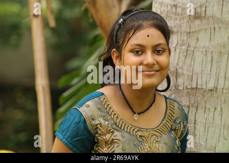 Ein junges, wunderschönes indisches Mädchen Porträt mit lächelndem Ausdruck und grüner Natur im Garten, Kopierbereich. Stockfoto