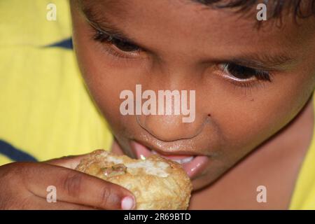 Der indische kleine Junge öffnet seinen Mund, um Wasserball zu essen Stockfoto