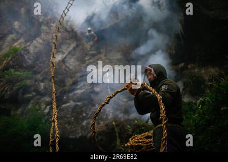 Sindhupalchowk, Nepal. 05. Juni 2023. Ein Honigjäger hilft bei der Honigjagd mit einem Seil, das an eine Klippe gefesselt ist. In den bezaubernden Hügeln Nepals entfaltet sich eine uralte Tradition namens Honigjagd, während mutige Individuen sich auf der Suche nach dem goldenen Nektar der Natur in die tückischen Klippen wagen. Mit nur einem Seil als Rettungsleine steigen diese Honigjäger in große Höhen und riskieren ihr Leben für die Chance, in den Höhen versteckte Honigwaben zu ernten. Die ländliche Gemeinde Bhotekhosi im Stadtteil Sindhupalchowk dient als ihr gewagter Spielplatz. Kredit: SOPA Images Limited/Alamy Live News Stockfoto