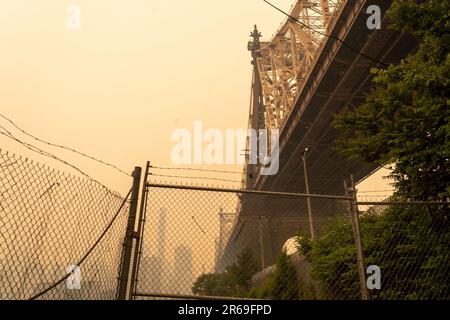 New York, New York, USA. 7. Juni 2023. (NEU) Rauch von kanadischen Waldbränden zieht in den Süden und erzeugt gefährliche Bedingungen auf großen Schwaden im Osten der USA 07. Juni 2023, New York, New York, USA: Mitten am Nachmittag wird die Queensboro Bridge (offiziell Ed Koch Queensboro Bridge genannt und auch als 59 Street Bridge bekannt) von Long Island City aus am 7. Juni 2023 im Stadtteil Queens von New York City aus mit Rauch aus dem kanadischen Waldbrand bedeckt. Am Dienstagabend stand New York an der Spitze der Liste der am meisten verschmutzten Großstädte der Welt, da der EAS weiterhin durch den Rauch der Brände bedeckt wird Stockfoto