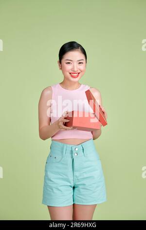 Emotionale brünette junge Frau öffnet die Geschenkbox, mit überfreulichem ekstatischem Gesichtsausdruck Stockfoto