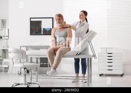 Orthopädin, der das Halsband am Hals des Patienten in der Klinik anlegt Stockfoto