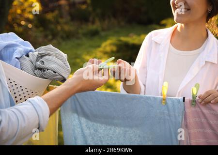 Glückliche Familie, die Kleidung aufhängt, mit Wäscheklammern an der Wäscheleine, zum Trocknen im Garten, Schließung Stockfoto